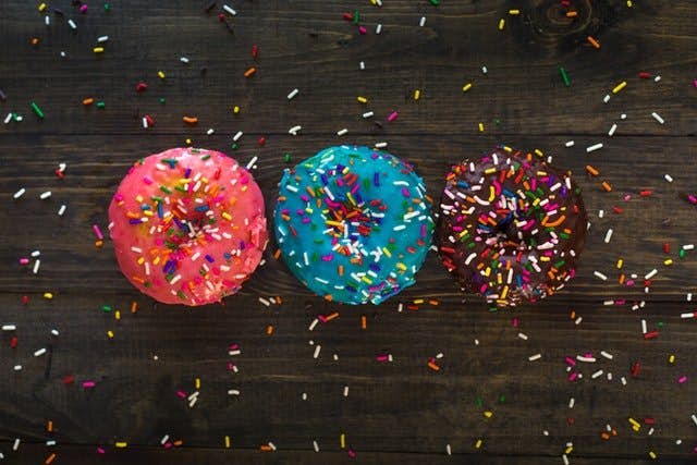 three donuts on table with sprinkles